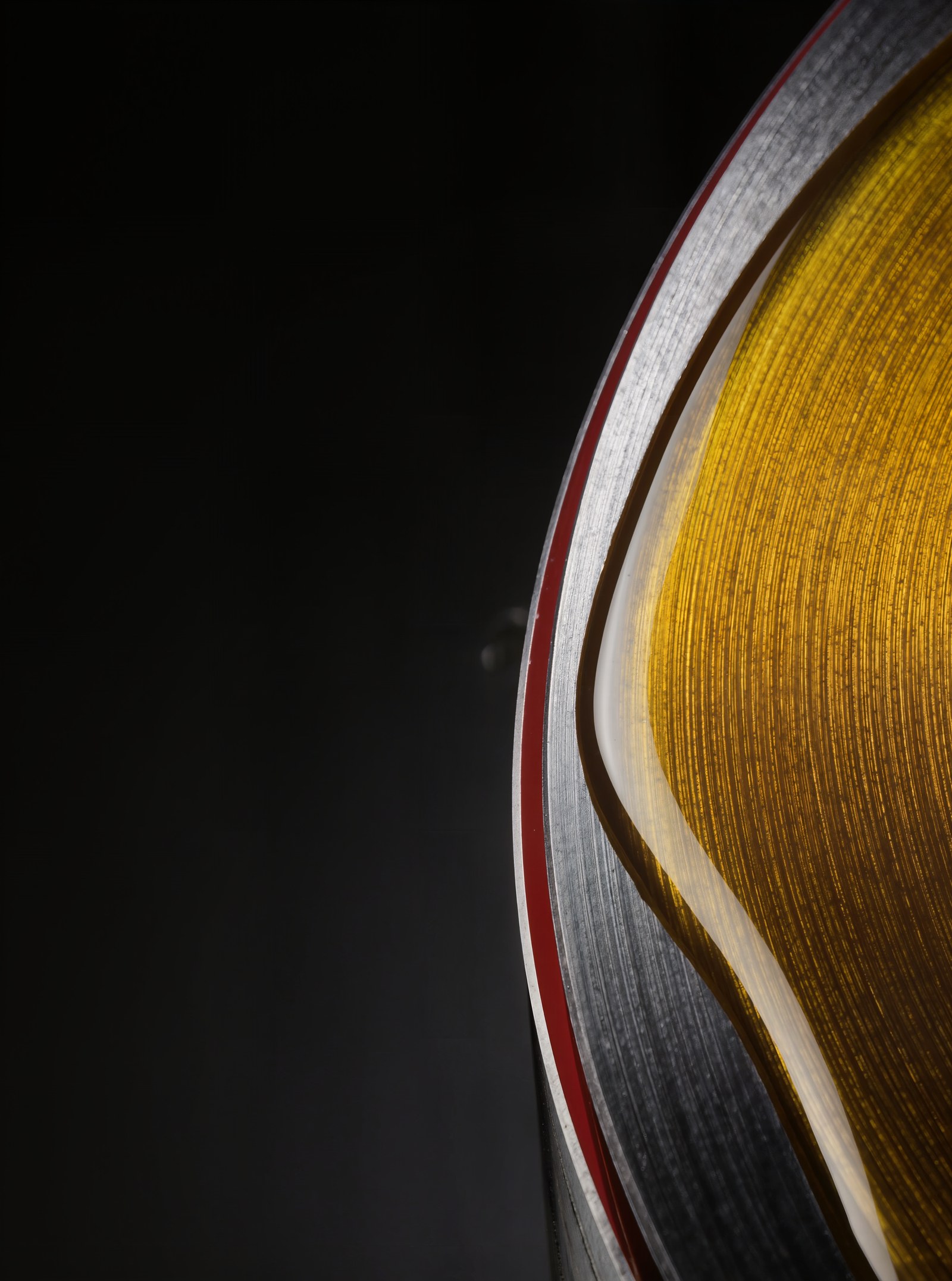 Macro detail of amber lubricant film spreading across a precision-machined steel surface